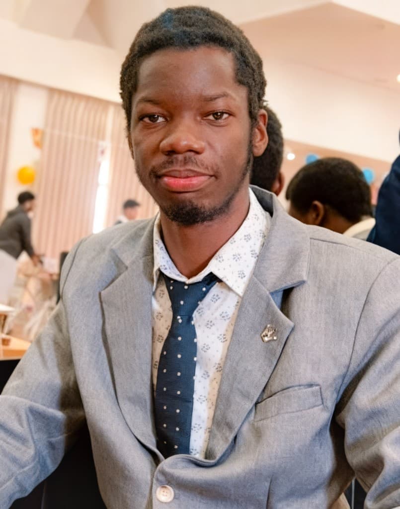 Francis Natus Mugisha — grey blazer portrait at a campus event
